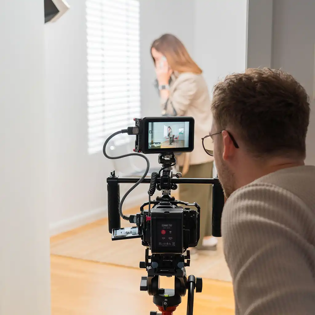 Produktionstag: professionelle Videokamera mit Viewfinder auf Stativ, gefilmtes Motiv im Hintergrund
